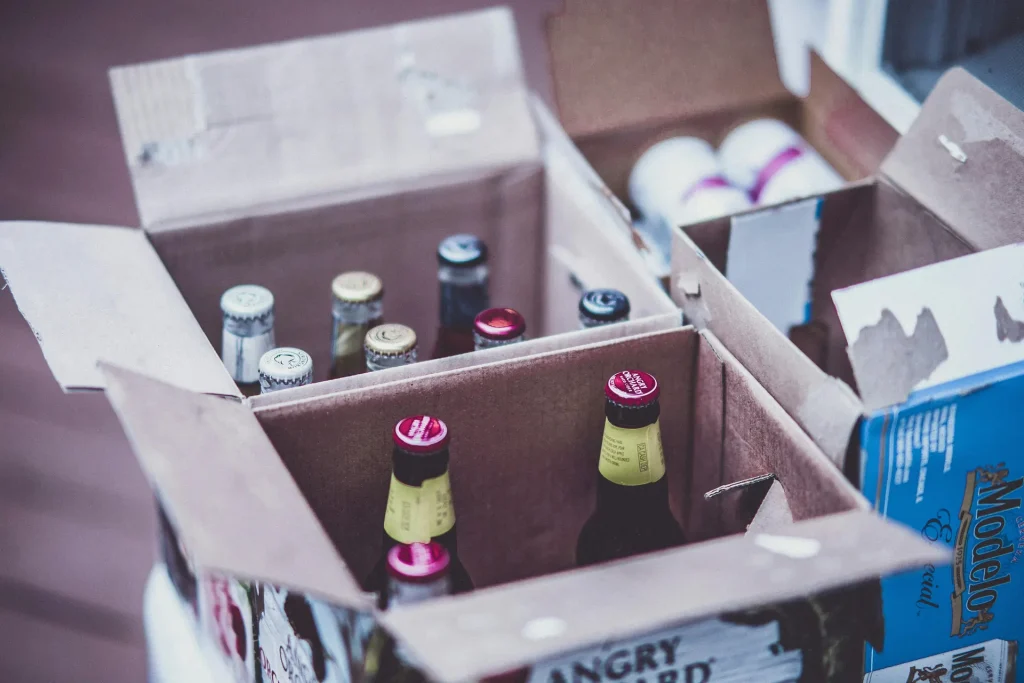 Cardboard boxes containing assorted beer bottles with visible bottle caps, including brands like Modelo Especial